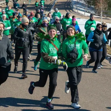 A group participants in a Shamrock Shuffle fundraiser dressed in festive green shirts and accessories showcasing community spirit